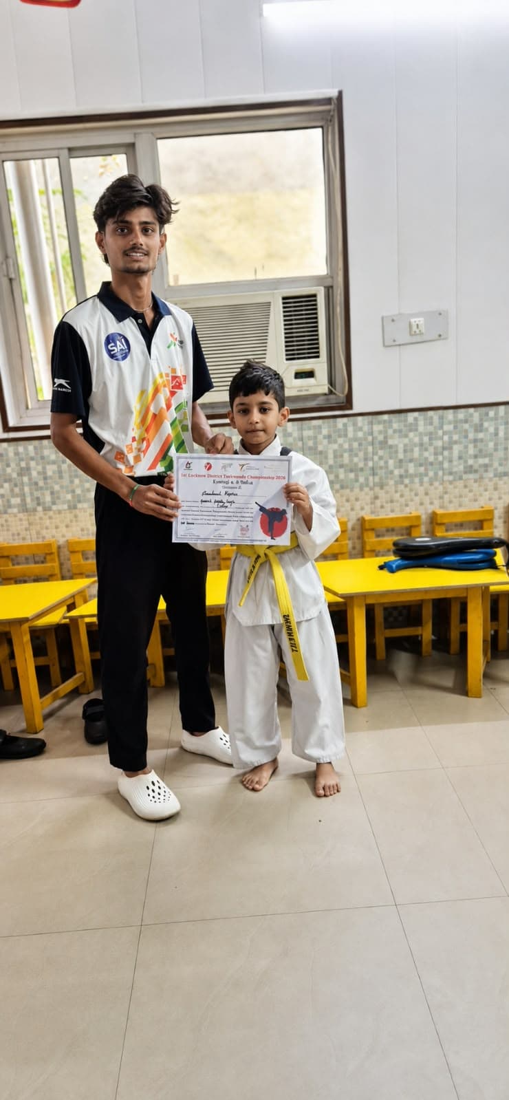 Utkarsh Tiwari presenting certificate to yellow belt student at 1st Lucknow District Taekwondo Championship